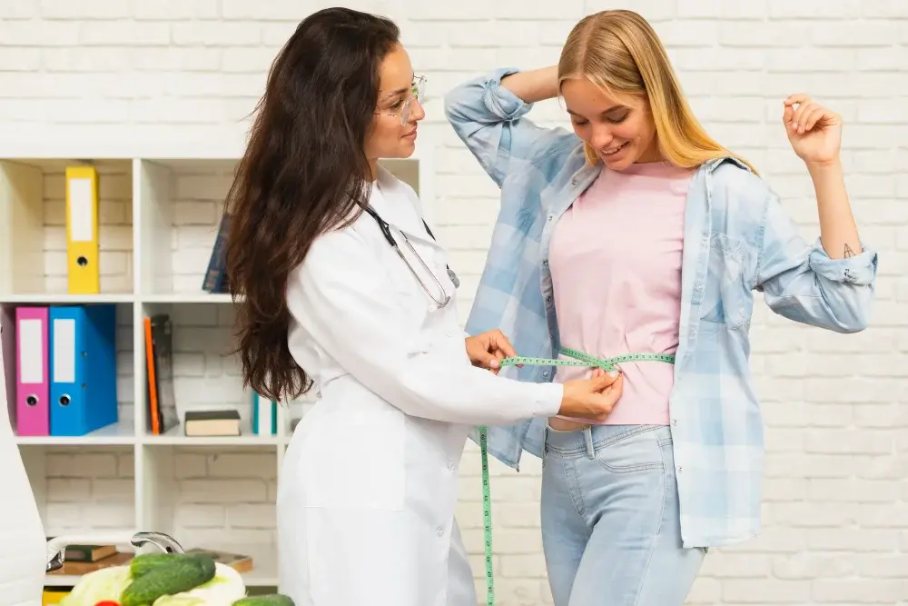 Doctor measuring a patient's waist during a weight loss consultation at Amen Family Medicine in Livonia, MI.