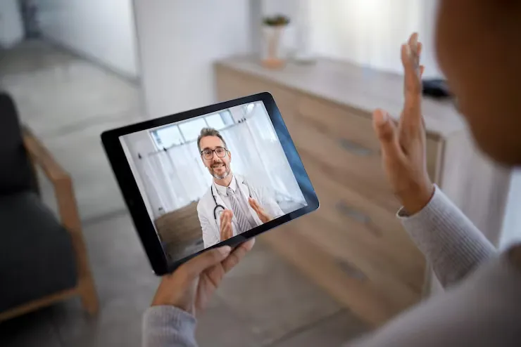 Patient holding a digital tablet during a telehealth primary care appointment with Dr. Hussen Amen.